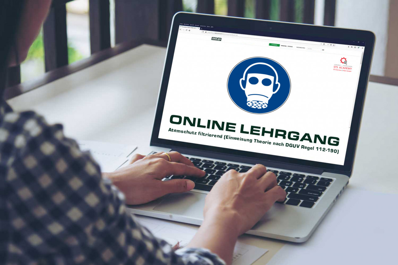 Auf dem Laptop ist ein Online-Lehrgang zum Thema Atemschutz zu sehen. Die Überschrift lautet "ONLINE LEHRGANG" und darunter steht "Atemschutz filtrierend (Einweisung Theorie nach DGUV Regel 112-190)". Eine Person nutzt den Laptop, um auf die Inhalte zuzugreifen.